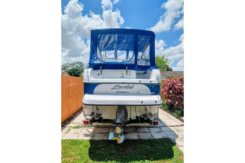 Slide: The Image of Rear view of 2000 Crownline 242 CR boat with blue canopy, parked on a sunny day. - 19