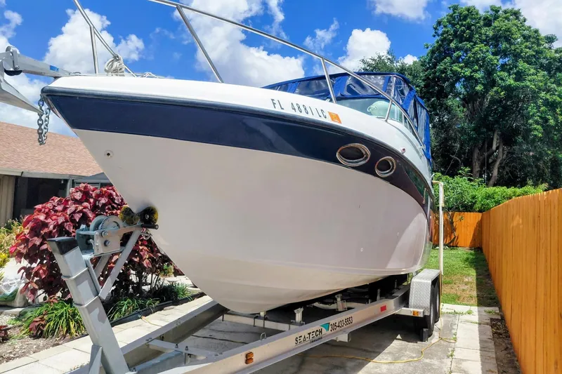 Slide: The Image of 2000 Crownline 242 CR boat on trailer, parked outdoors with blue sky background. - 2