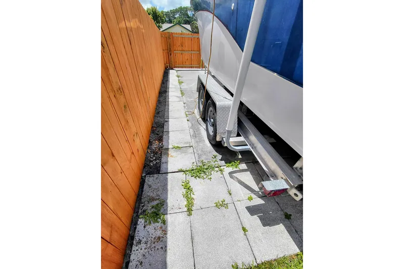 Slide: The Image of Crownline 242 CR boat from 2000 parked on a paved driveway beside a wooden fence. - 23