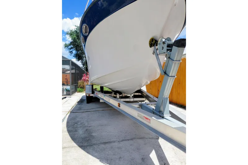 Slide: The Image of 2000 Crownline 242 CR boat on trailer, parked in driveway under clear blue sky. - 5