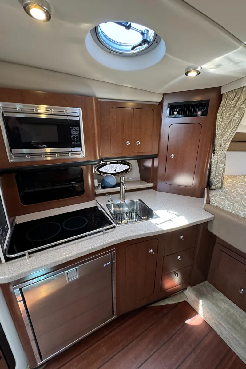 Slide: The Image of 2018 Crownline 350 SY yacht kitchen with modern appliances and wood cabinetry. - 52