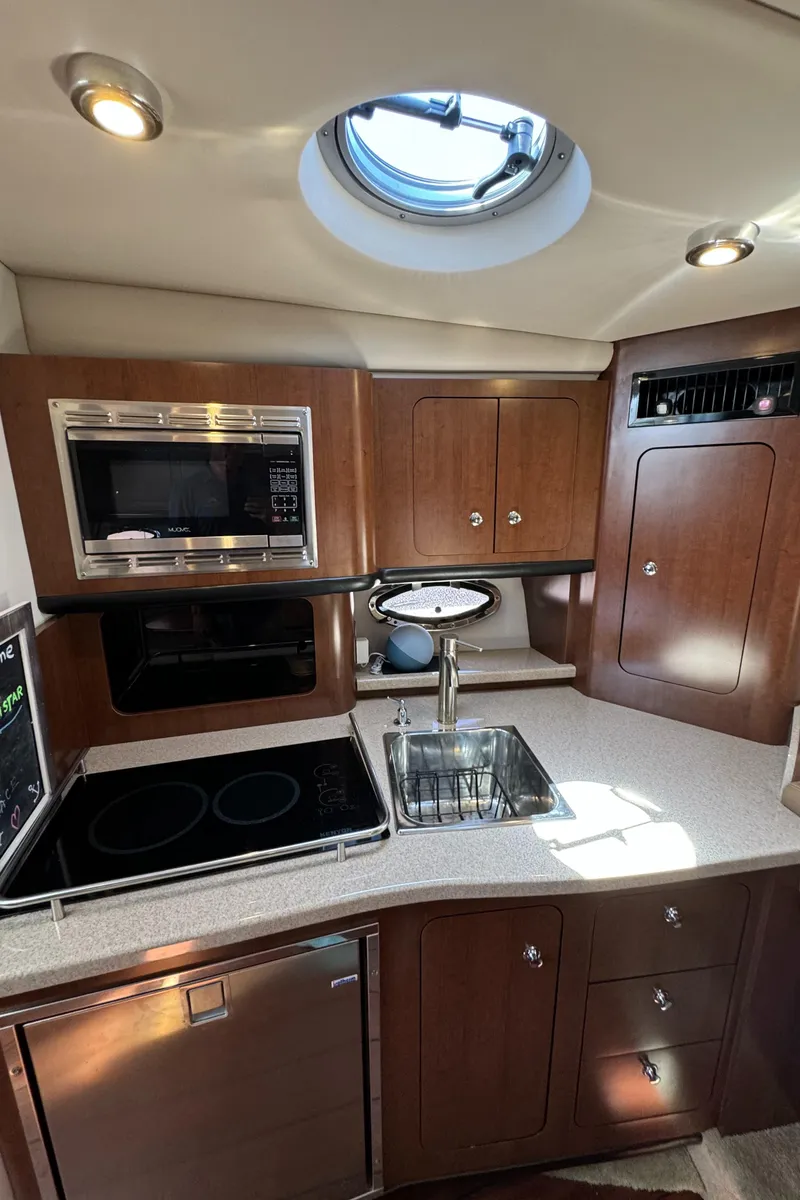 Slide: The Image of 2018 Crownline 350 SY yacht kitchen with modern appliances and wood cabinetry. - 53