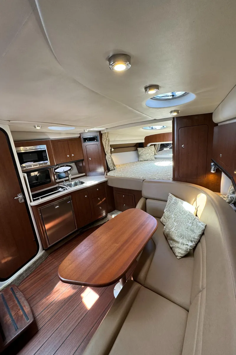 Slide: The Image of 2018 Crownline 350 SY yacht interior with kitchen, dining area, and bed. - 54