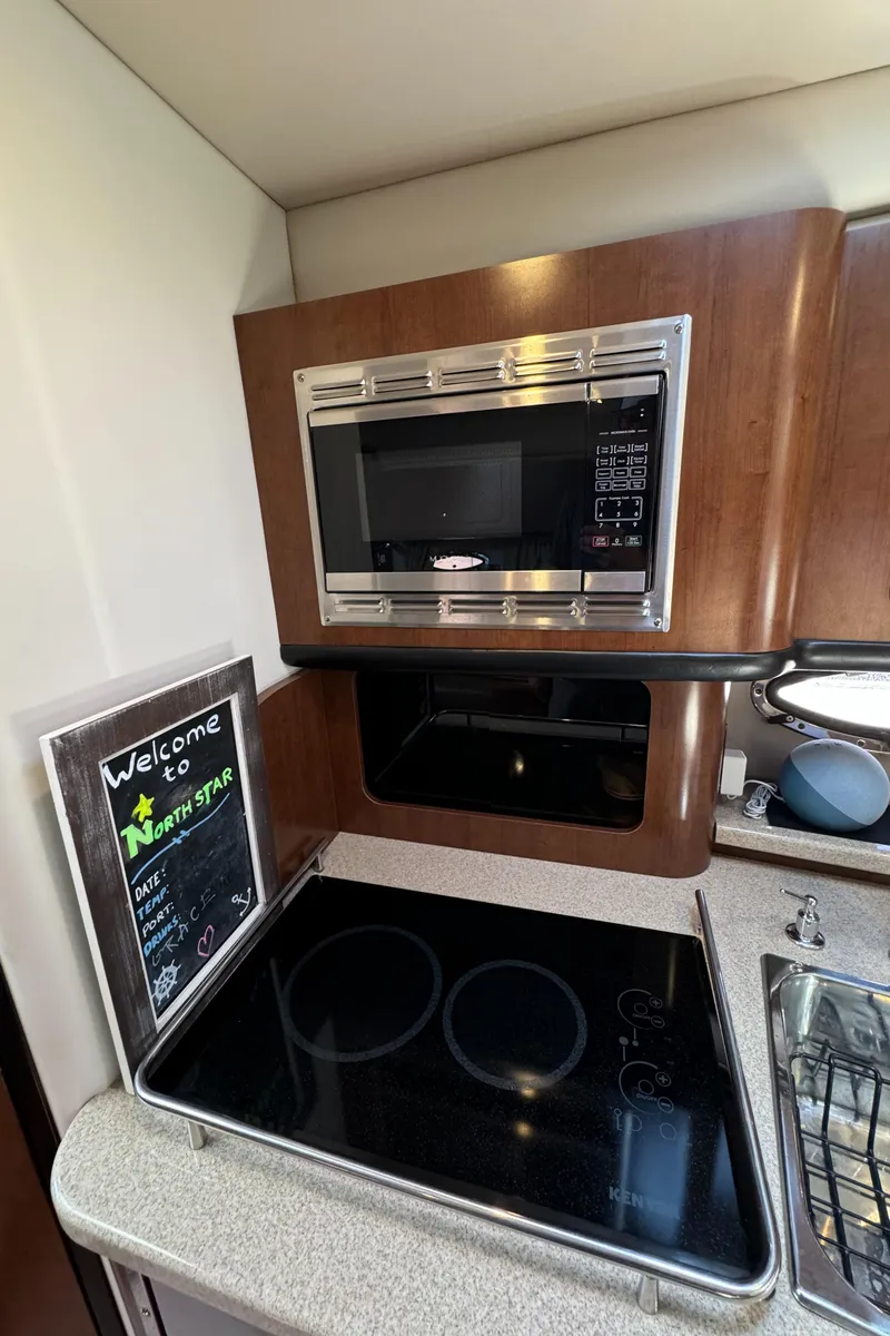 Slide: The Image of 2018 Crownline 350 SY kitchen with microwave, stovetop, and welcome sign. - 56