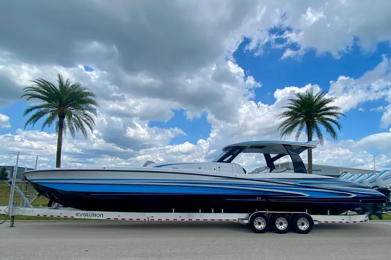 The Image of 2024 MTI V50 boat on trailer under cloudy sky with palm trees. - 0