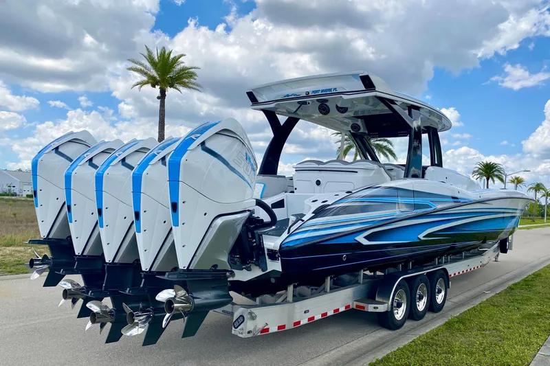 Slide: The Image of 2024 MTI V50 boat with quad engines on a trailer under a partly cloudy sky. - 2
