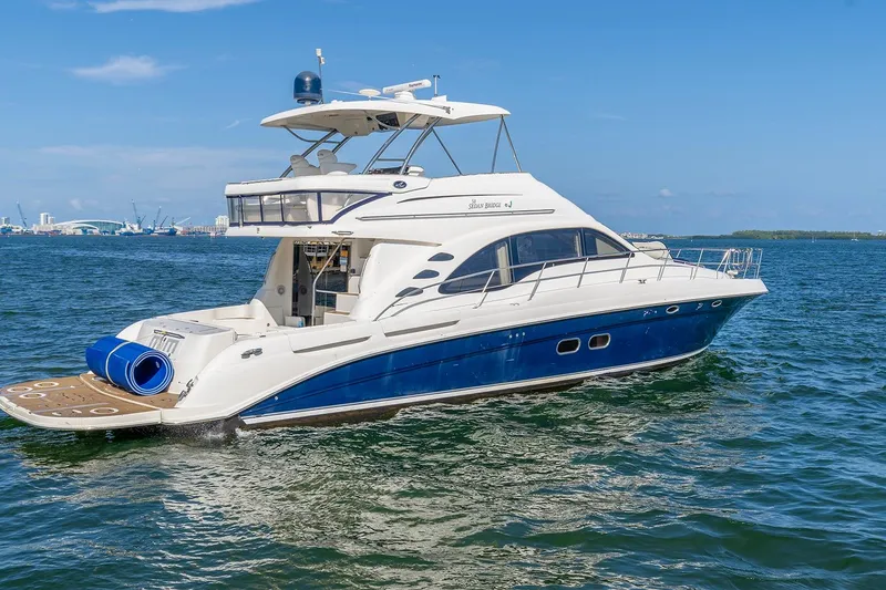The Image of 2006 Sea Ray 58 Sedan Bridge yacht cruising on open water under clear blue skies. - 0