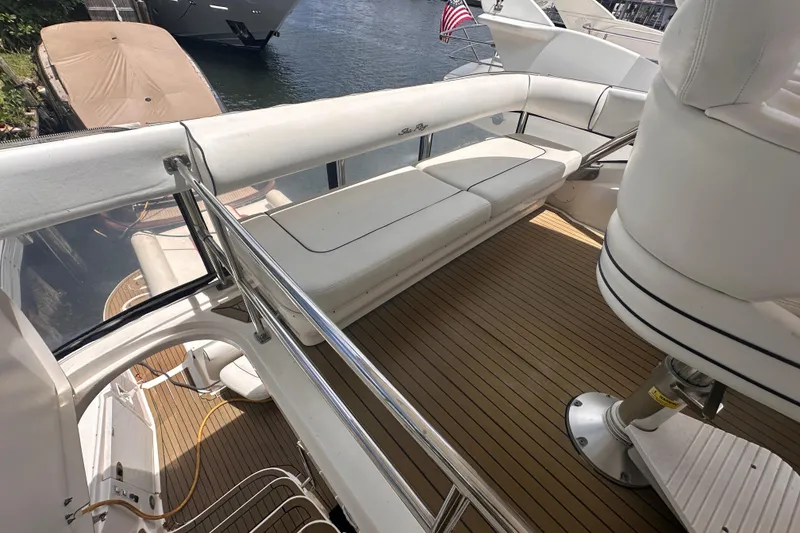 Slide: The Image of 2006 Sea Ray 58 Sedan Bridge yacht deck with white seating and wooden flooring. - 13