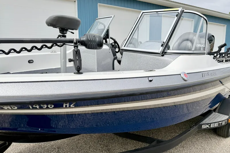 Slide: The Image of 2012 Skeeter SL 185 boat with blue and white exterior, parked on a trailer. - 13