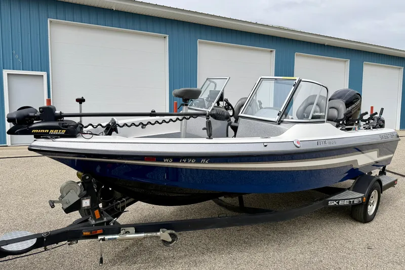 Slide: The Image of 2012 Skeeter SL 185 boat with trailer, parked outside blue building. - 3
