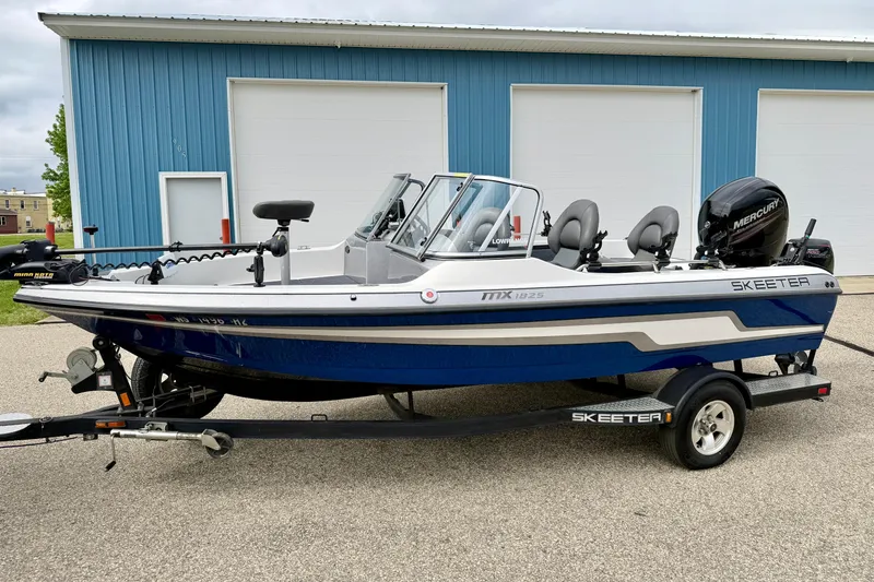 Slide: The Image of 2012 Skeeter SL 185 boat with Mercury engine, parked on trailer near blue building. - 5