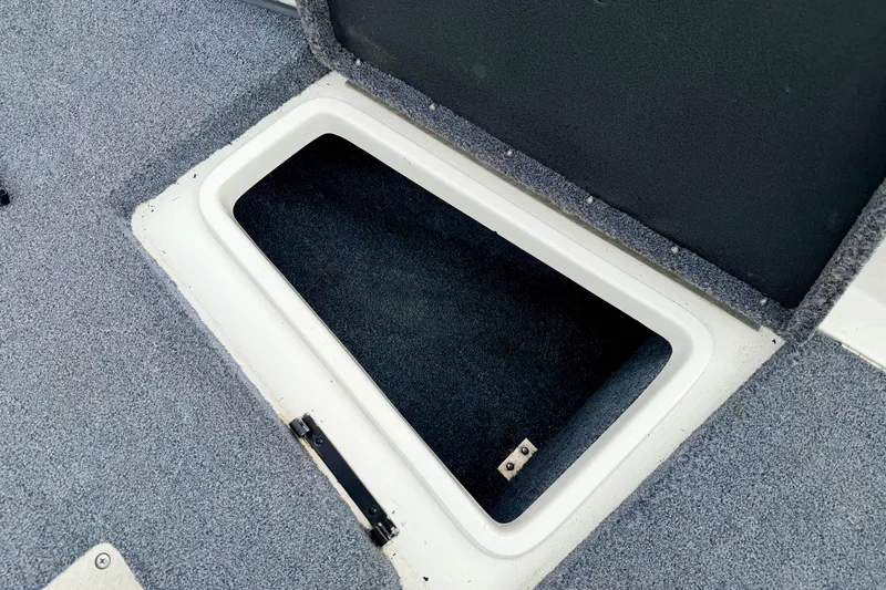 Slide: The Image of Open storage compartment on a 2012 Skeeter SL 185 boat, featuring carpeted interior. - 53