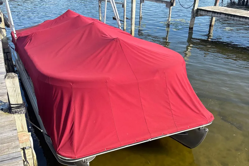 Slide: The Image of Covered 2011 Harris Cruiser 200 pontoon boat docked on calm water. - 2