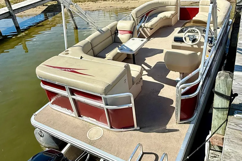 Slide: The Image of 2011 Harris Cruiser 200 pontoon boat docked, featuring beige seating and red accents. - 6