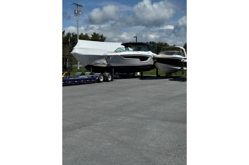 Slide: The Image of 2024 Cruisers Yachts 38 GLS OB on trailer, parked outdoors under cloudy sky. - 13