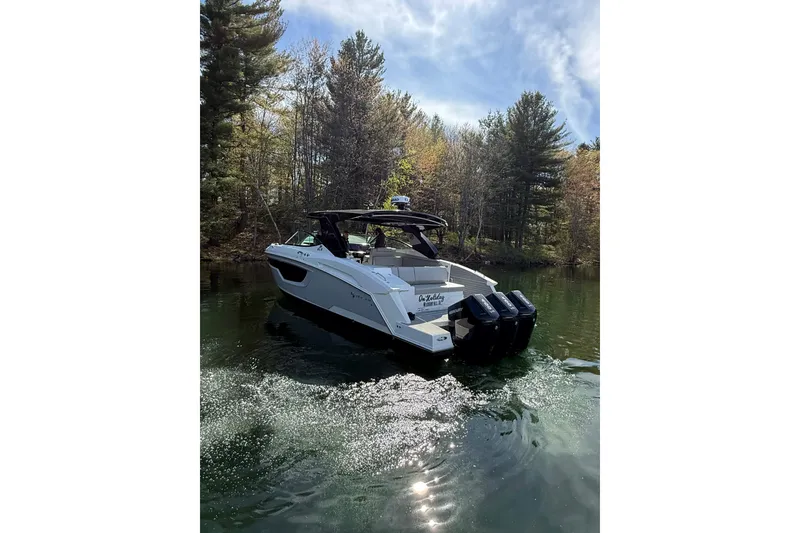 Slide: The Image of 2024 Cruisers Yachts 38 GLS OB on a serene lake, surrounded by lush trees. - 4