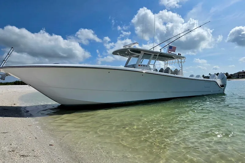 Slide: The Image of 2023 Invincible 46 Catamaran on sandy beach with clear water and blue sky. - 2