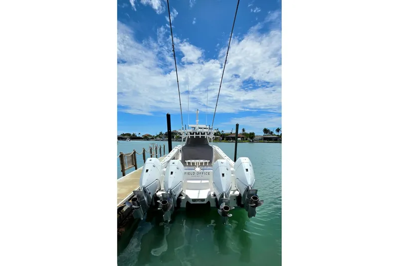 Slide: The Image of 2023 Invincible 46 Catamaran docked, featuring four powerful outboard engines under a clear blue sky. - 4