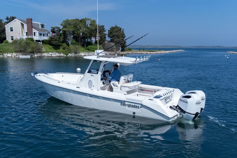 Slide: The Image of 2011 Everglades 295 Center Console boat cruising near a coastal home. - 10