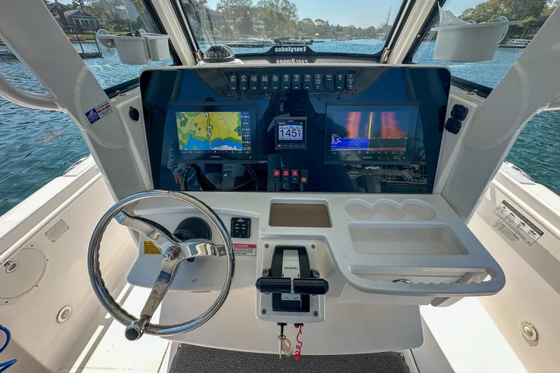 Slide: The Image of 2011 Everglades 295 Center Console boat dashboard with navigation screens and steering wheel. - 23
