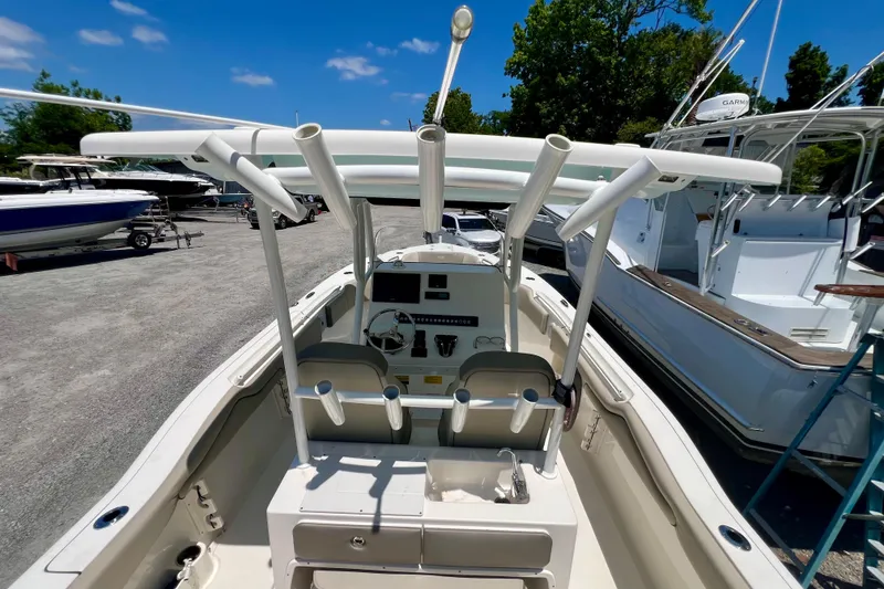 Slide: The Image of 2023 Key West 263 FS boat interior with helm, rod holders, and seating under a clear blue sky. - 21