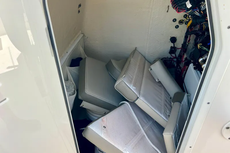 Slide: The Image of Interior of 2023 Key West 263 FS boat showing storage area with cushions and wiring. - 24