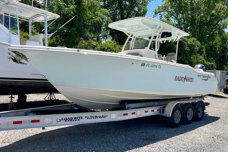 Slide: The Image of 2023 Key West 263 FS boat on trailer, parked outdoors, with trees in background. - 3