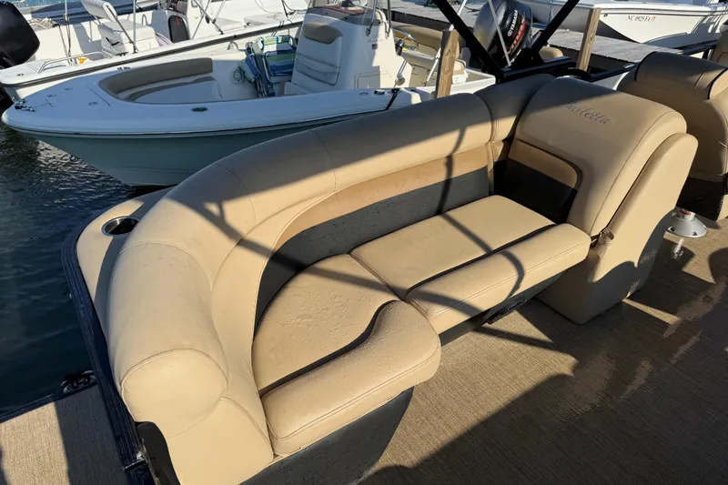 Slide: The Image of 2021 Barletta C22QC pontoon boat with beige seating and cup holder, docked beside another boat. - 17