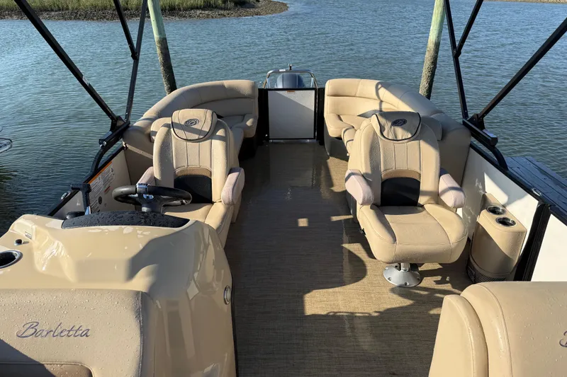Slide: The Image of 2021 Barletta C22QC pontoon boat interior with beige seating and steering wheel. - 8