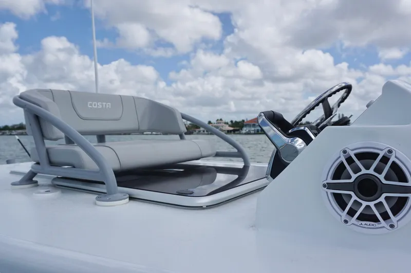 Slide: The Image of 2024 Costa Custom Boats 264HC helm with seating and audio system on a sunny day. - 27