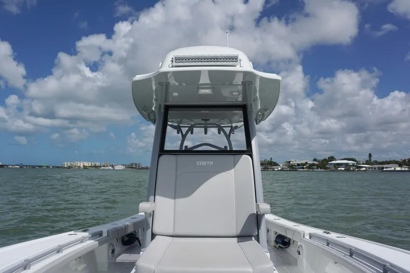 Slide: The Image of 2024 Costa Custom Boats 264HC on water, showcasing helm and seating under a cloudy sky. - 32