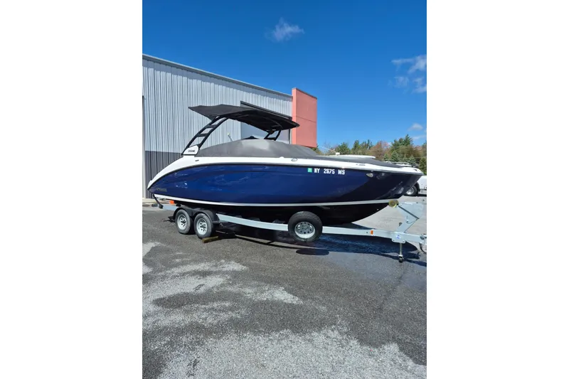 The Image of 2021 Yamaha Boats 252SE on trailer, blue hull, parked outdoors under clear sky. - 1