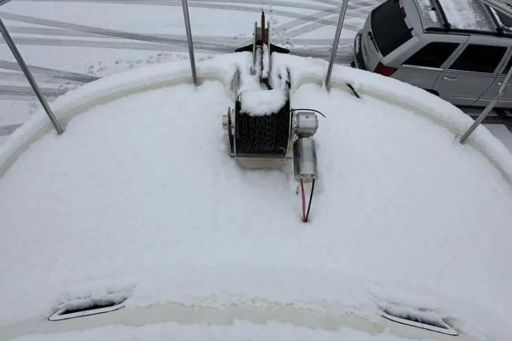 Slide: The Image of Snow-covered deck of a 2000 SeaSport Pacific 3200 boat, with a winch and nearby vehicle. - 15