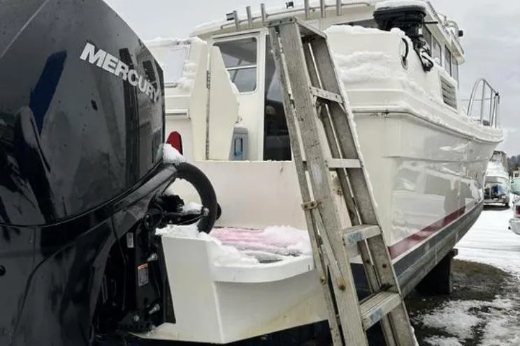 Slide: The Image of SeaSport Pacific 3200 boat, 2000 model, with Mercury engine, covered in snow, ladder nearby. - 22