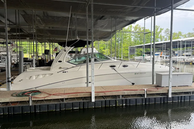 The Image of 2003 Sea Ray 340 Sundancer docked in a marina under a covered slip. - 0