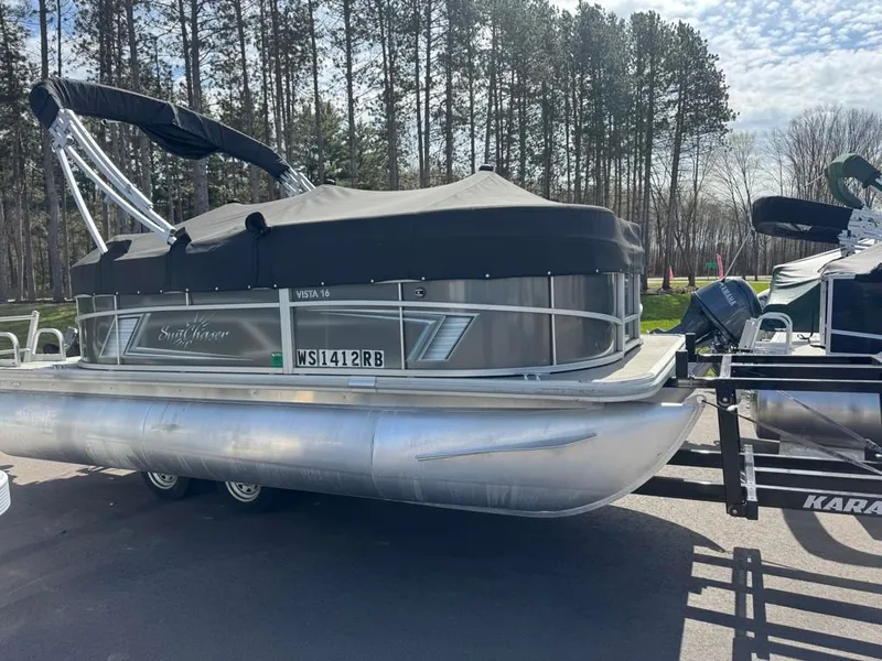 The Image of 2021 SunCatcher Vista 16 pontoon boat on trailer outdoors. - 1