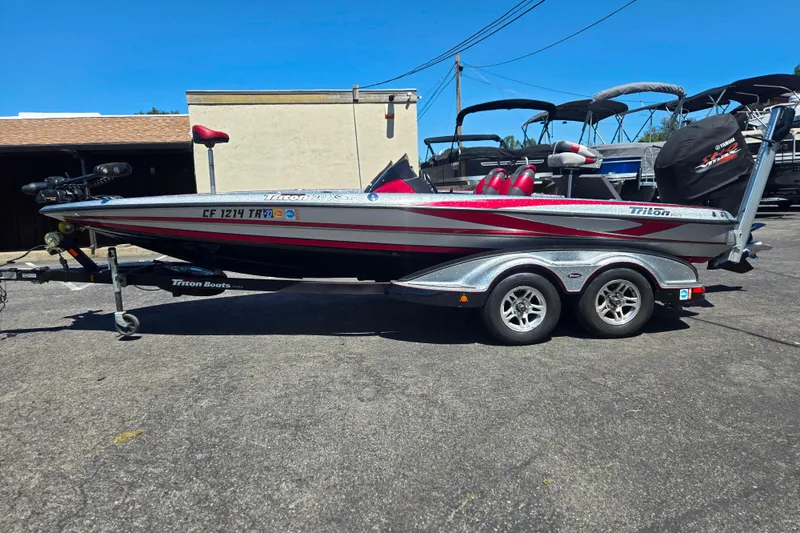 The Image of 2011 Triton 20XS DC boat on trailer, parked outdoors, featuring sleek design and red accents. - 1