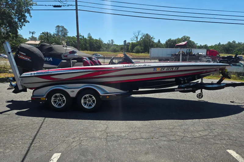 Slide: The Image of 2011 Triton 20XS DC boat on trailer, parked outdoors under clear sky. - 2