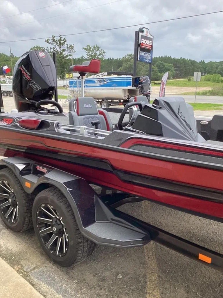 Slide: The Image of 2026 Bass Cat Eyra boat on trailer, red and black, parked outdoors. - 25