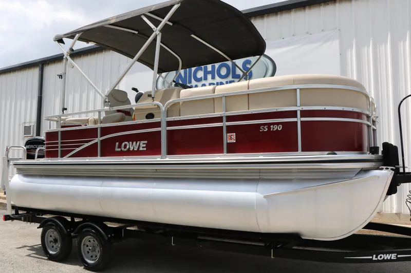 The Image of 2016 Lowe SS190 pontoon boat on trailer outside warehouse. - 1