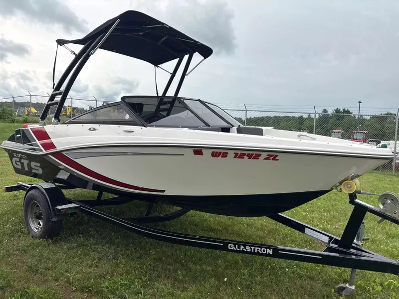Slide: The Image of A 2019 Glastron GTS185 boat on a trailer, featuring a black canopy and sporty design. - 2