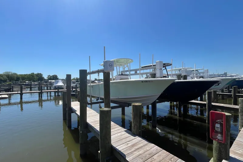 The Image of 2021 Sportsman Heritage 231 Center Console boat docked at a marina under clear blue skies. - 1