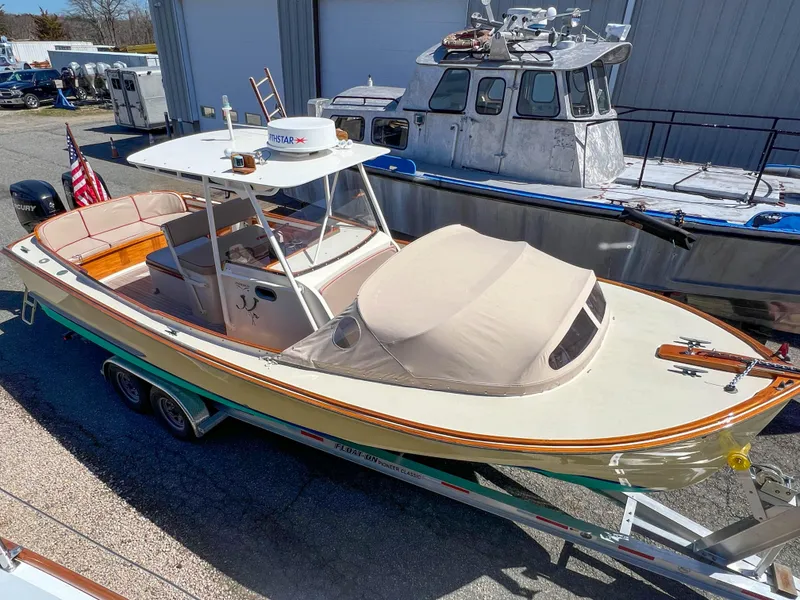 Slide: The Image of 2003 Padebco V27 Center Console boat on trailer, beige canopy, American flag displayed. - 11