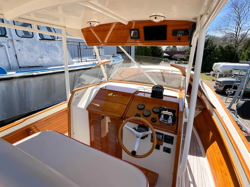 Slide: The Image of 2003 Padebco V27 Center Console boat interior with wooden dashboard and steering wheel. - 16