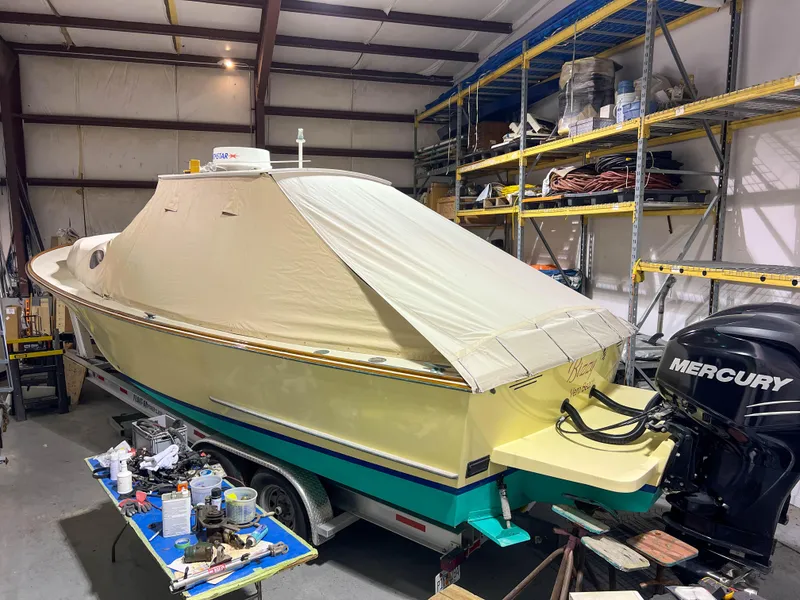 Slide: The Image of 2003 Padebco V27 Center Console boat with cover in storage, featuring Mercury outboard engine. - 41