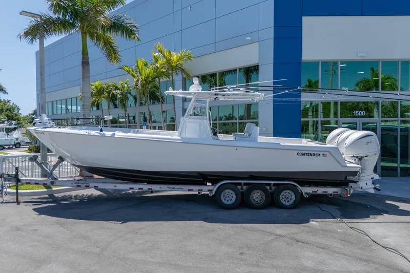 The Image of 2024 Contender 35 ST boat on trailer outside modern building with palm trees. - 0