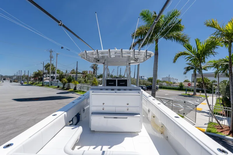 Slide: The Image of 2024 Contender 35 ST boat with center console, docked near palm trees under clear blue sky. - 24