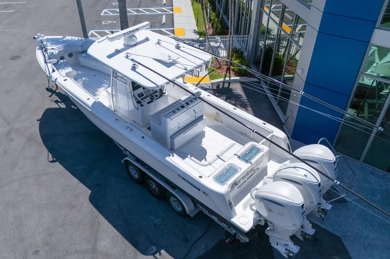 Slide: The Image of 2024 Contender 35 ST boat with triple engines, parked near a modern building. - 3