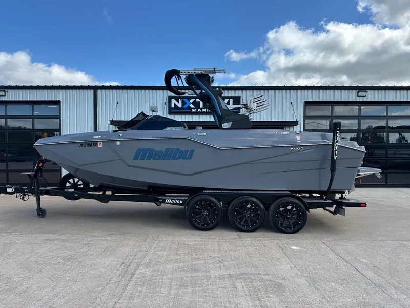 The Image of 2024 Malibu M242 boat on trailer in front of building. - 1