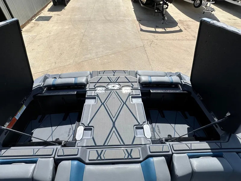 Slide: The Image of 2024 Malibu M242 boat with open storage compartments and cushioned seating. - 48